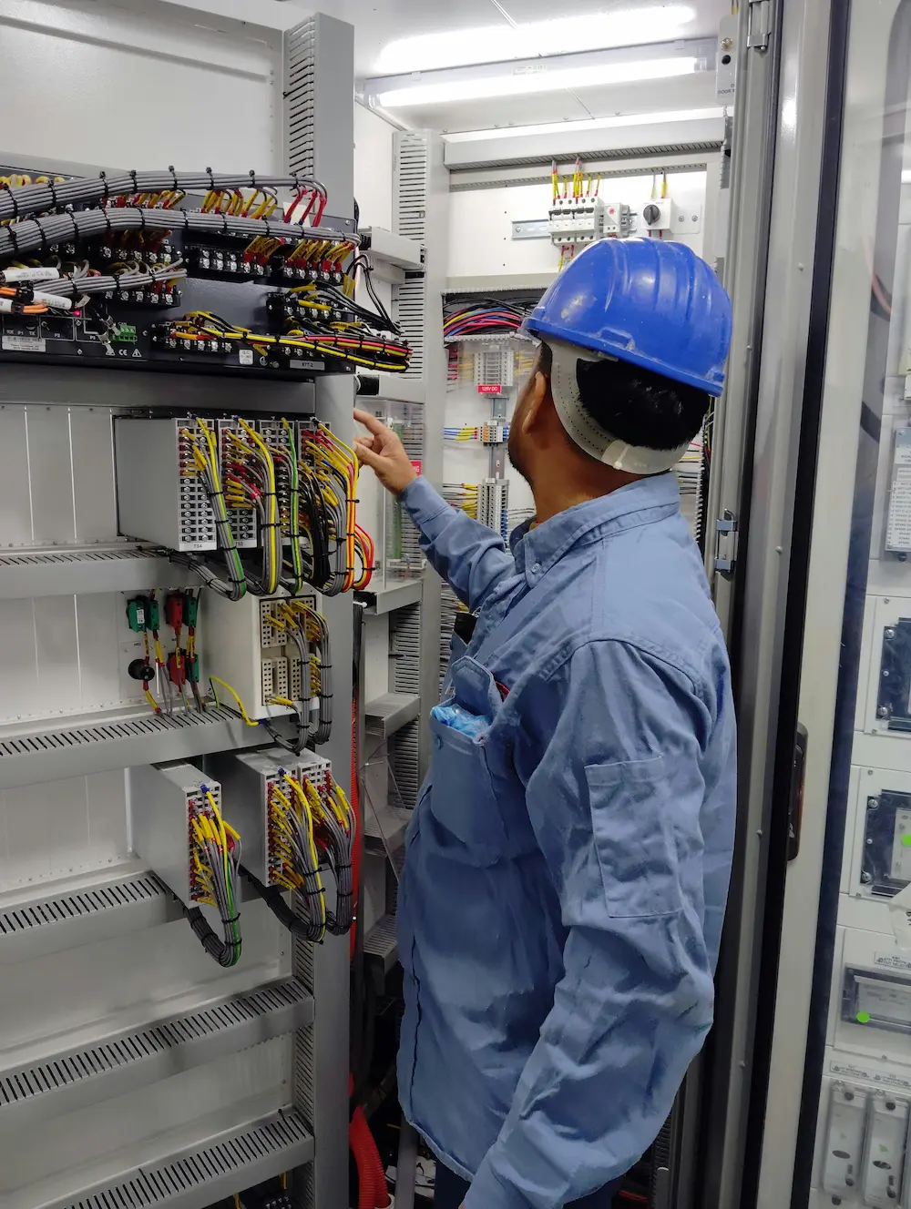 Engineer inspecting industrial control panel wiring with terminal blocks
